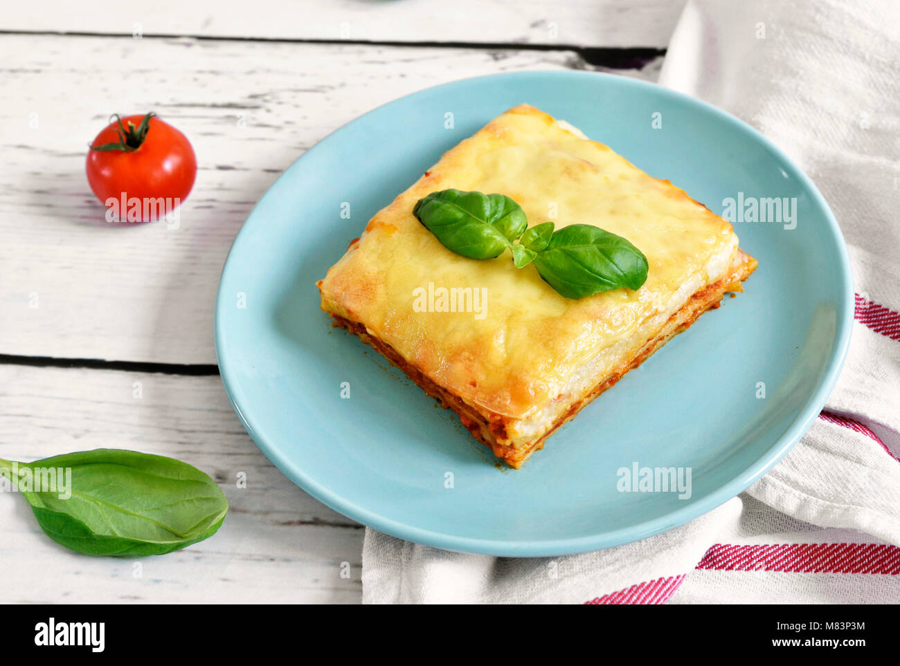 Fresh meat lasagne, lasagne bolognese, pasta dish on a wooden table with decorative basil leaf. Italian cuisine. Stock Photo
