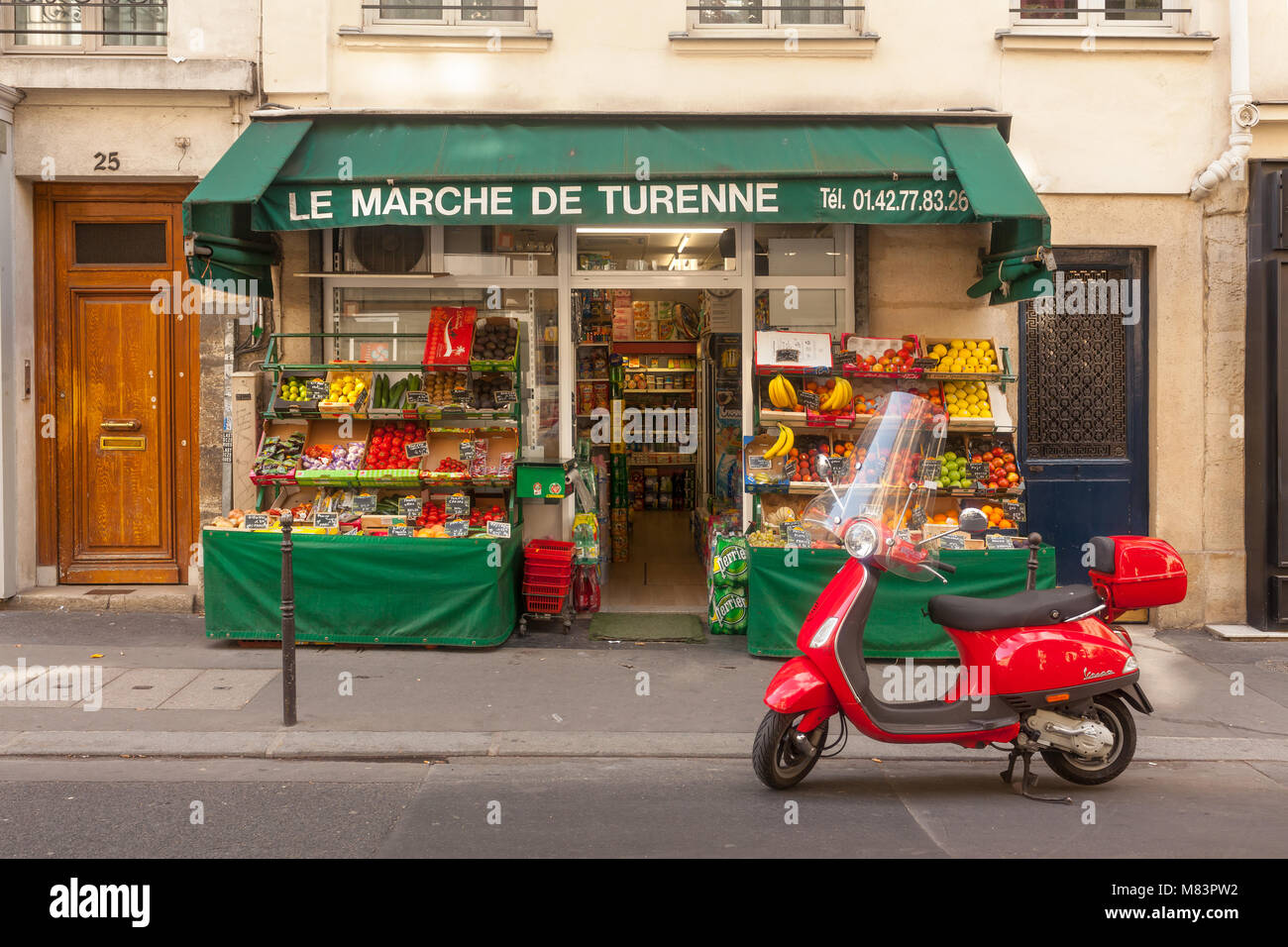 Small grocery store in Paris. Red motor scooter stands in front of it