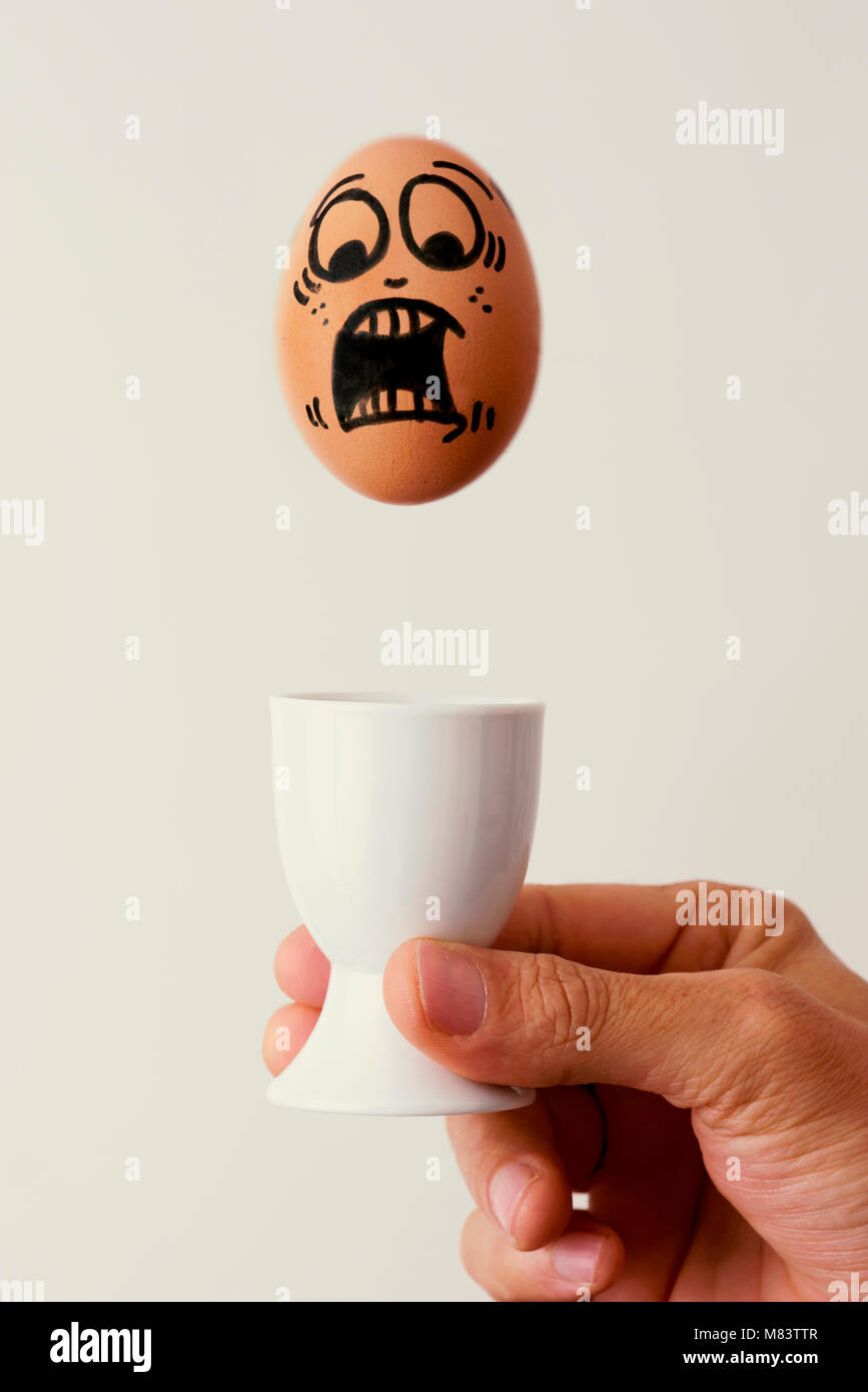 Happy Different Individual Concept Single Egg With Smiley Face In Striped Egg  Cup In Front Of Ten Boiled Eggs In White Egg Cups On A Wooden Table Stock  Photo - Download Image