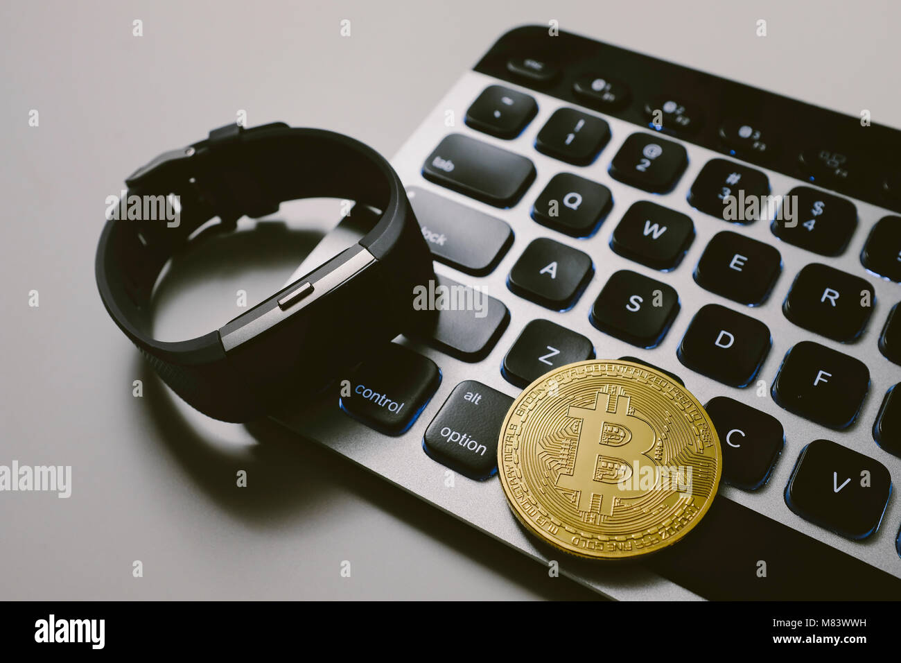 Bitcoin on keyboard with fitness tracker watch Stock Photo
