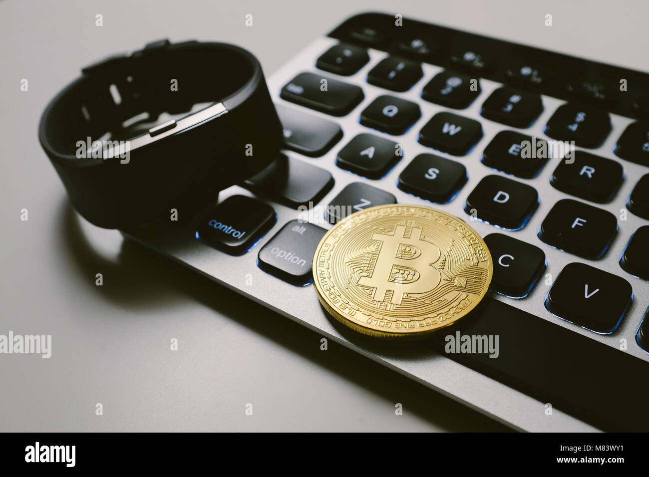 Bitcoin on keyboard with fitness tracker watch Stock Photo