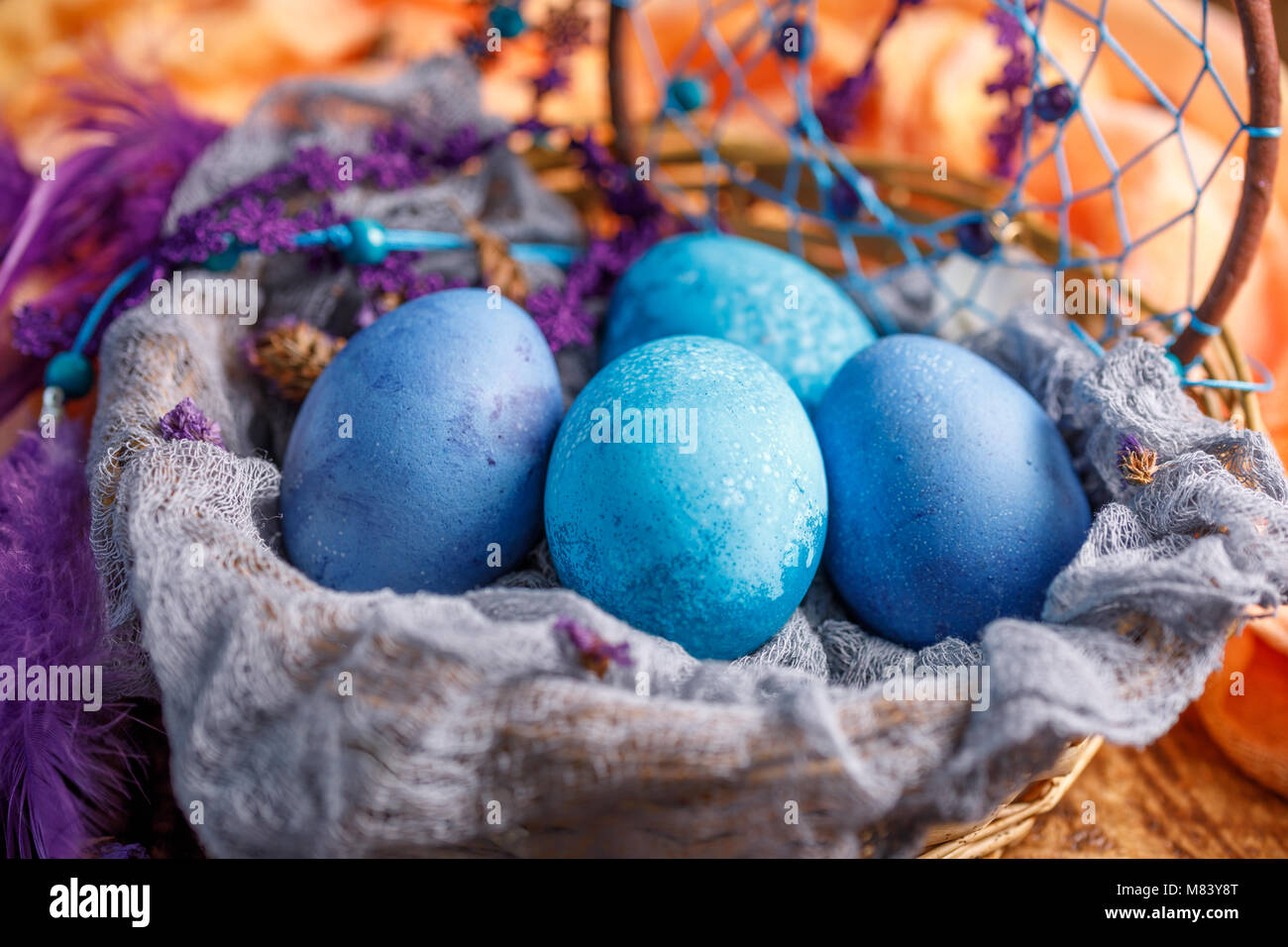 Eggs in a wicker basket are painted in an unusual blue color. Easter ...