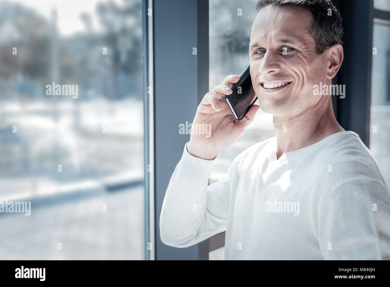 Pleasant joyful man having phone conversation and smiling. Stock Photo