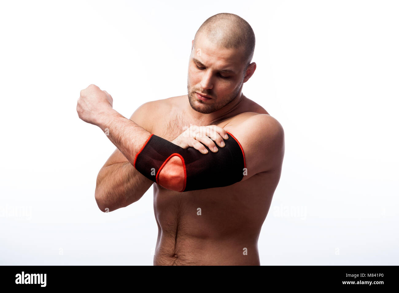 Injury of the elbow. Young bald man sportive physique holds a sick elbow in the armrest on a white isolated background Stock Photo