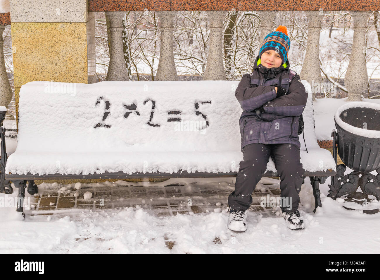 Naughty boy wrongly decides an example on a snow-covered bench Stock Photo