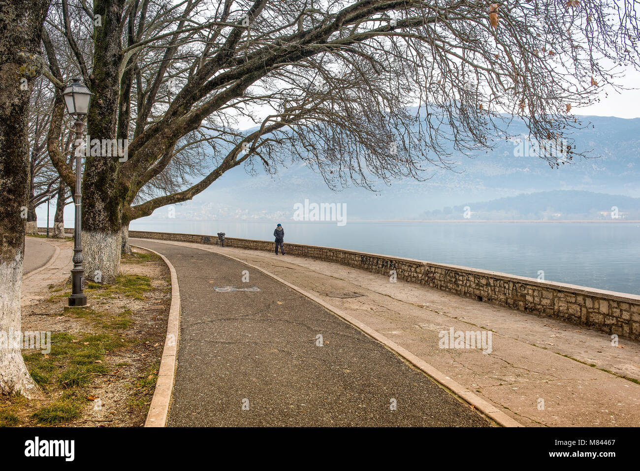 Foggy morning on lake Pamvotis. Alone woman on a road for pedestrians and bicycles .Ioannina ,Greece Stock Photo
