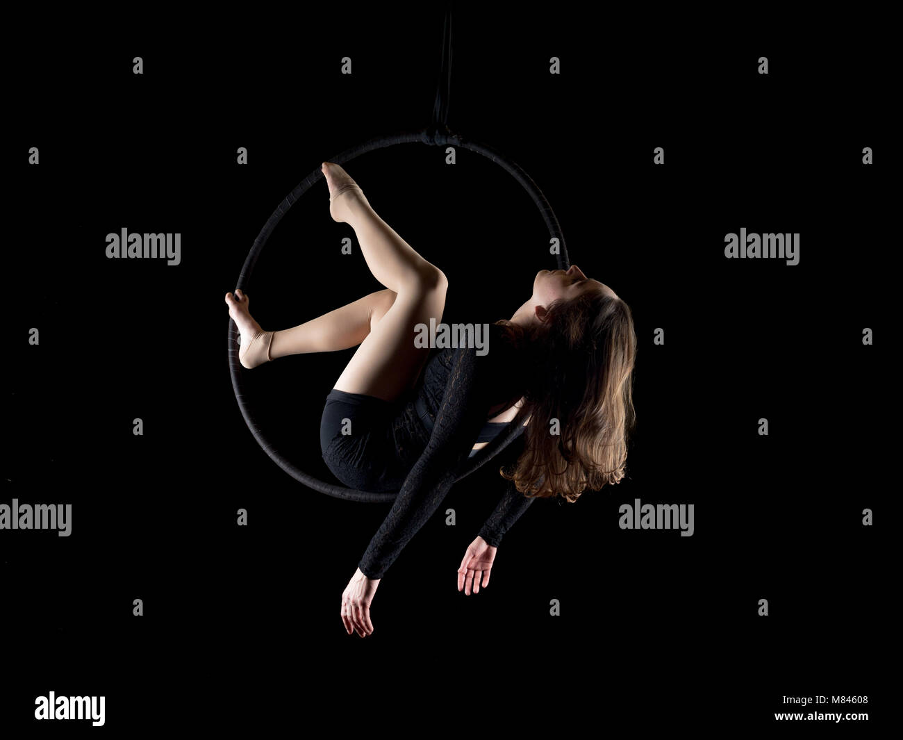 Graceful aerial dancer woman doing her performance with a hoop isolated