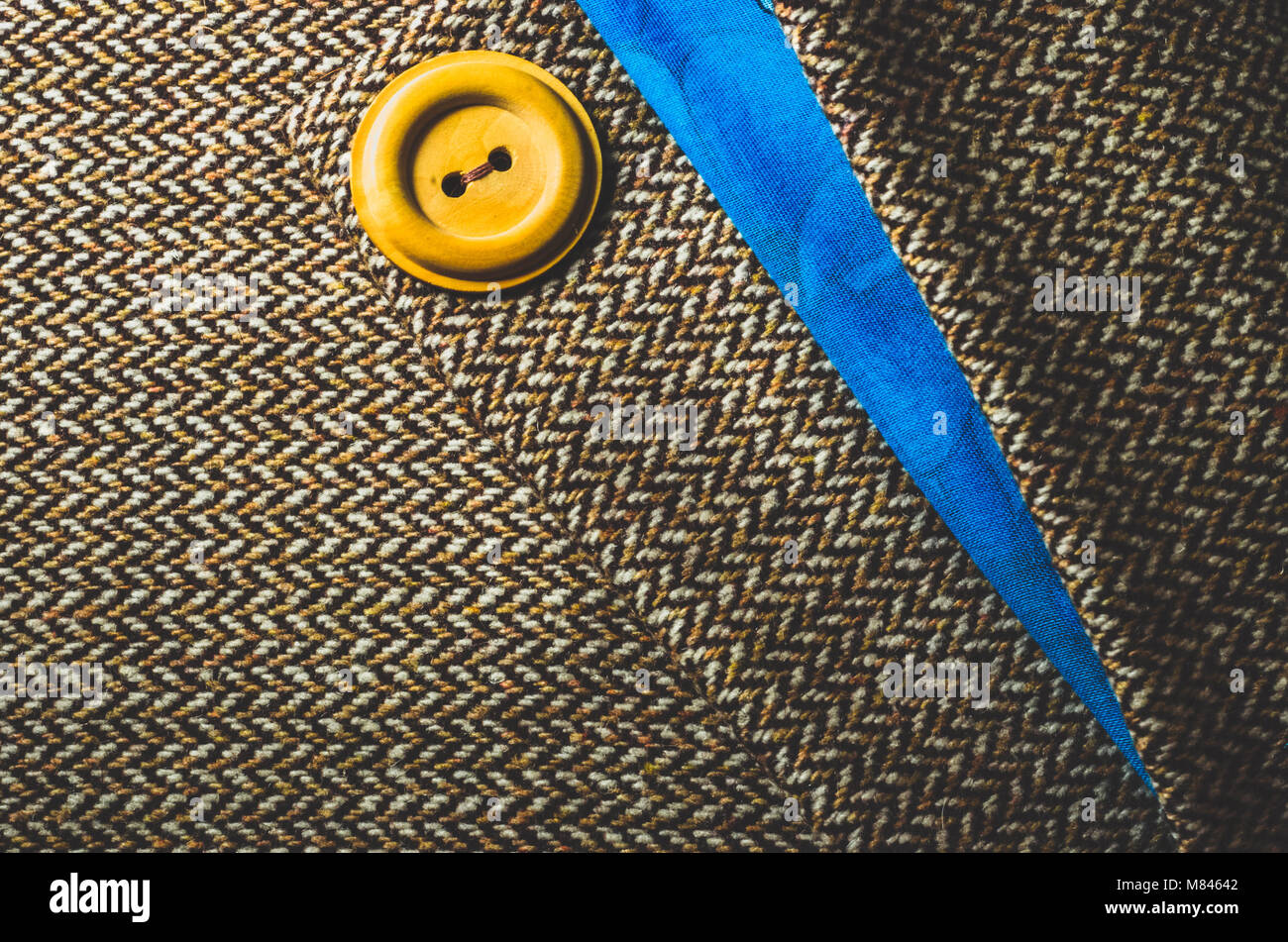 Yellow button on folded brown and blue fabric Stock Photo