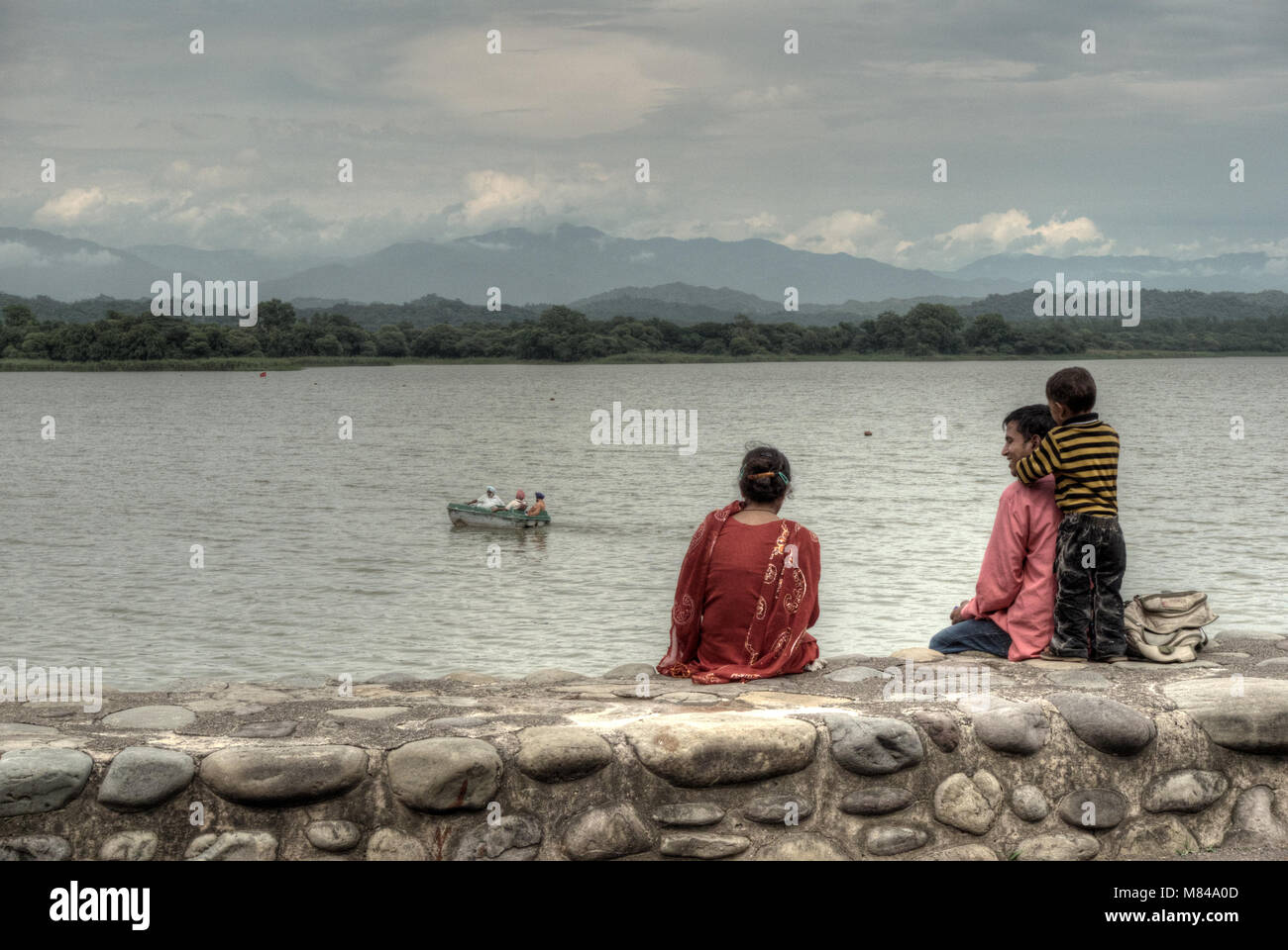 Chandigarh, India: a young Indian couple with their son sit on the shores of Sukhna Lake in the city of Chandigarh, Penjab, India Stock Photo