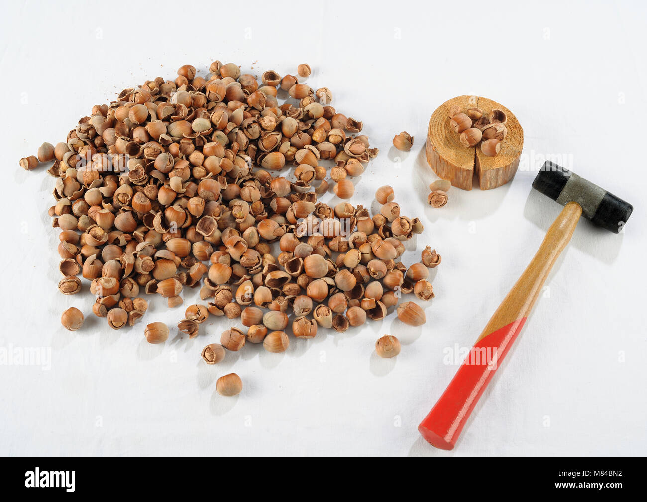 Crack hazelnuts with a hammer on the white table Stock Photo - Alamy