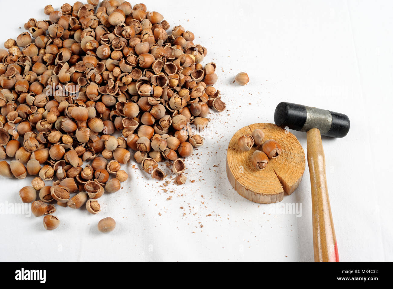 Crack hazelnuts with a hammer on the white table Stock Photo - Alamy