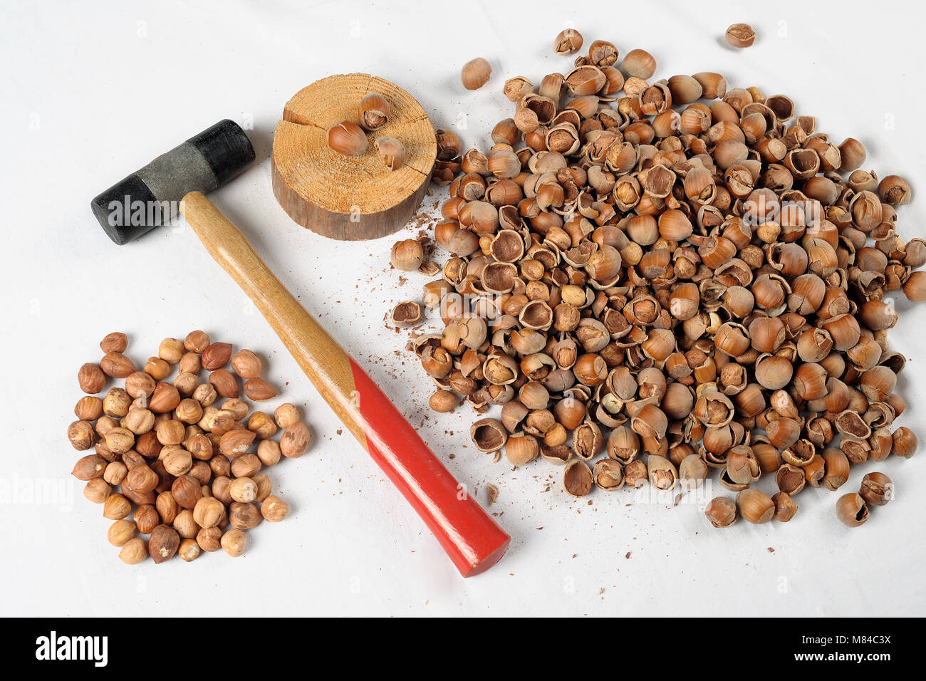 Crack hazelnuts with a hammer on the white table Stock Photo - Alamy