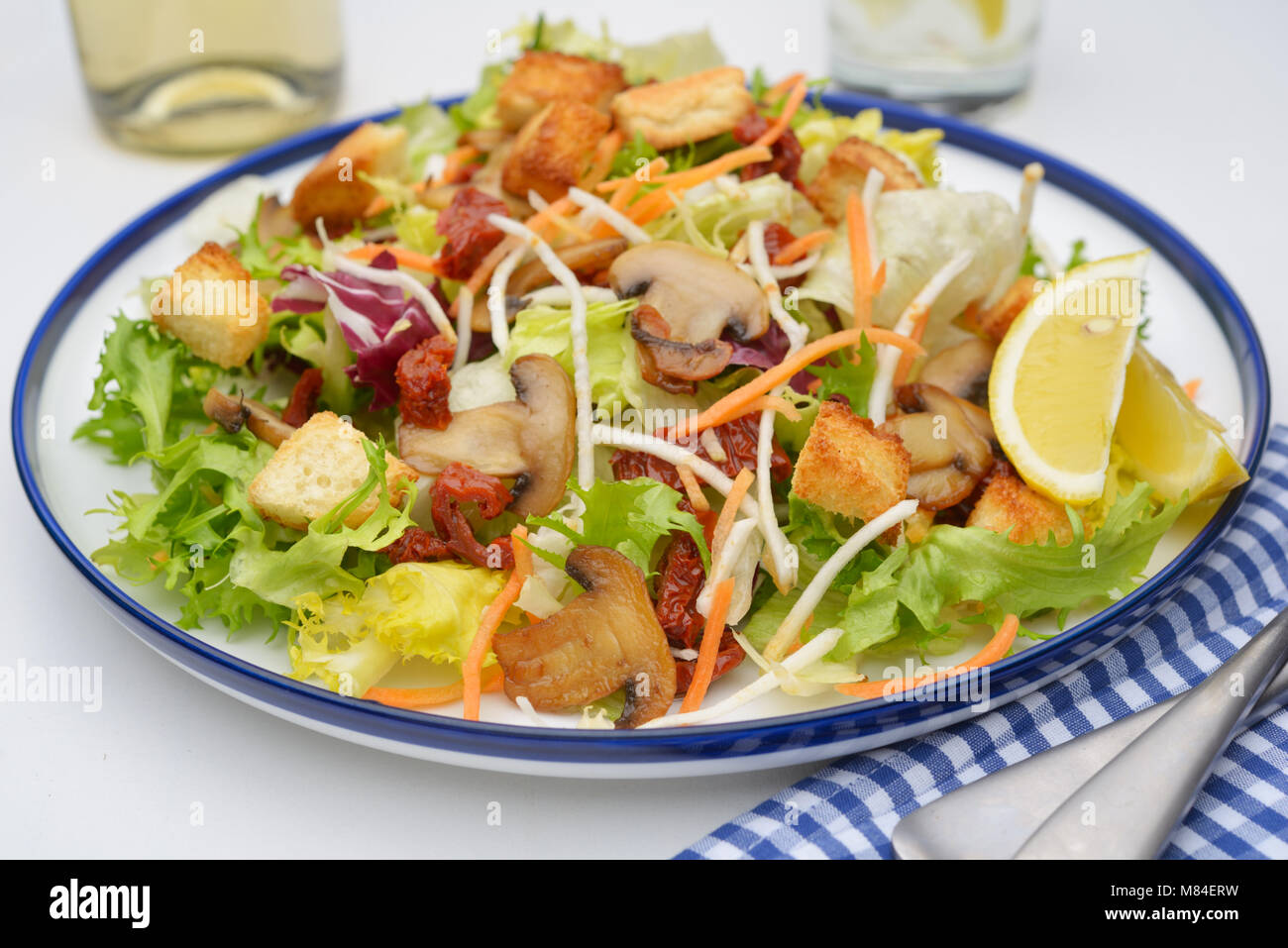 Salad with lettuce, roasted mushrooms, croutons, dried tomatoes, and lemon Stock Photo