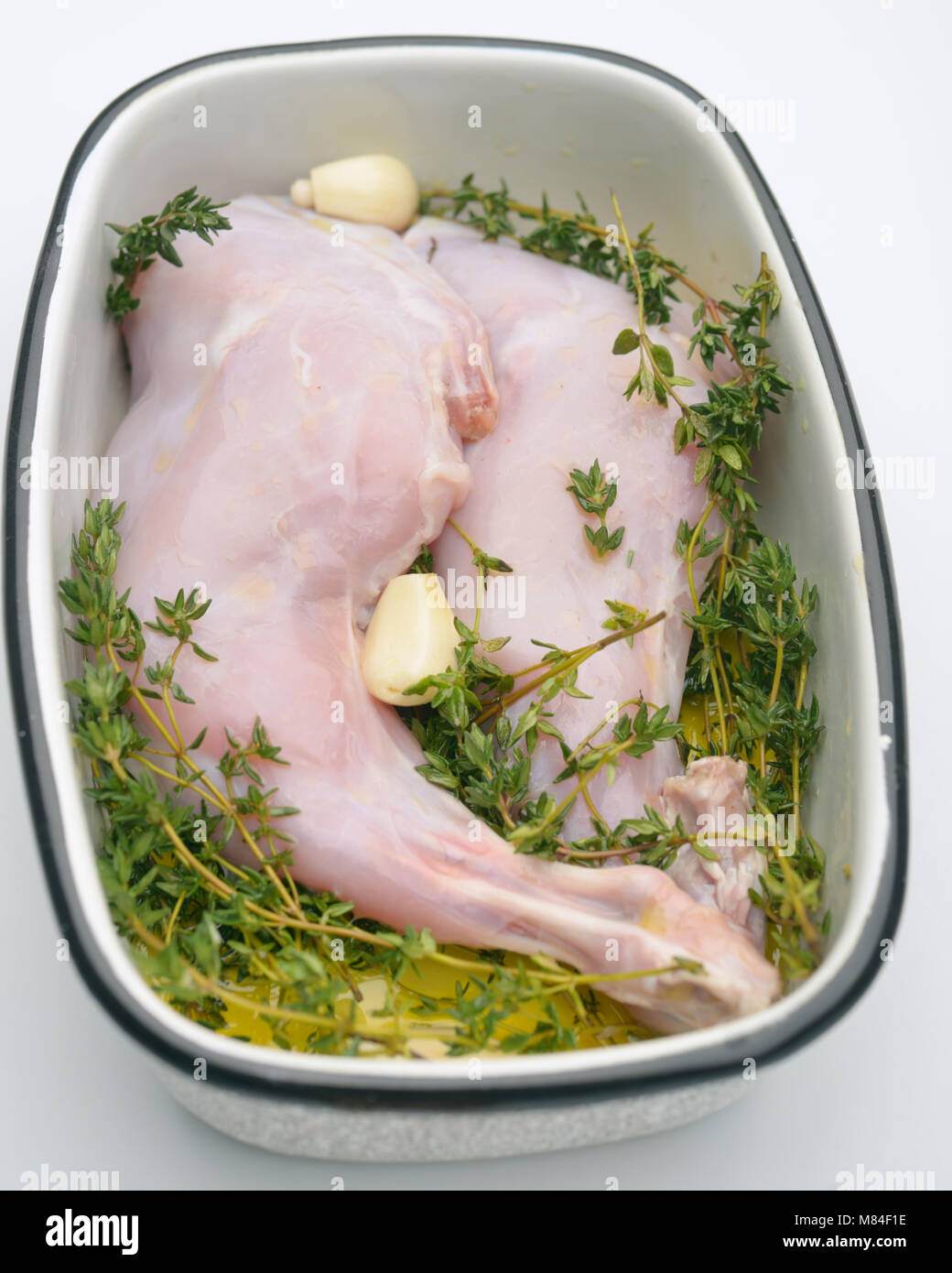 Raw rabbit leg with garlic, thyme, and olive oil Stock Photo - Alamy