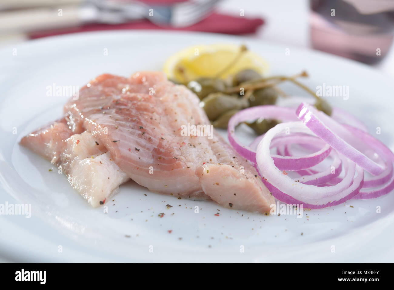 Marinated herring with red onion, capers, and lemon Stock Photo