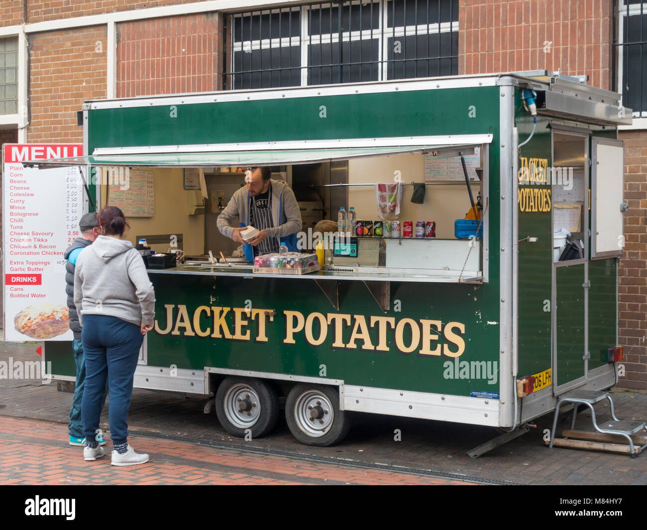 A couple buying food from a Jacket Potato stall in Gilkes Street Middlesbrough on a busy shopping day Stock Photo
