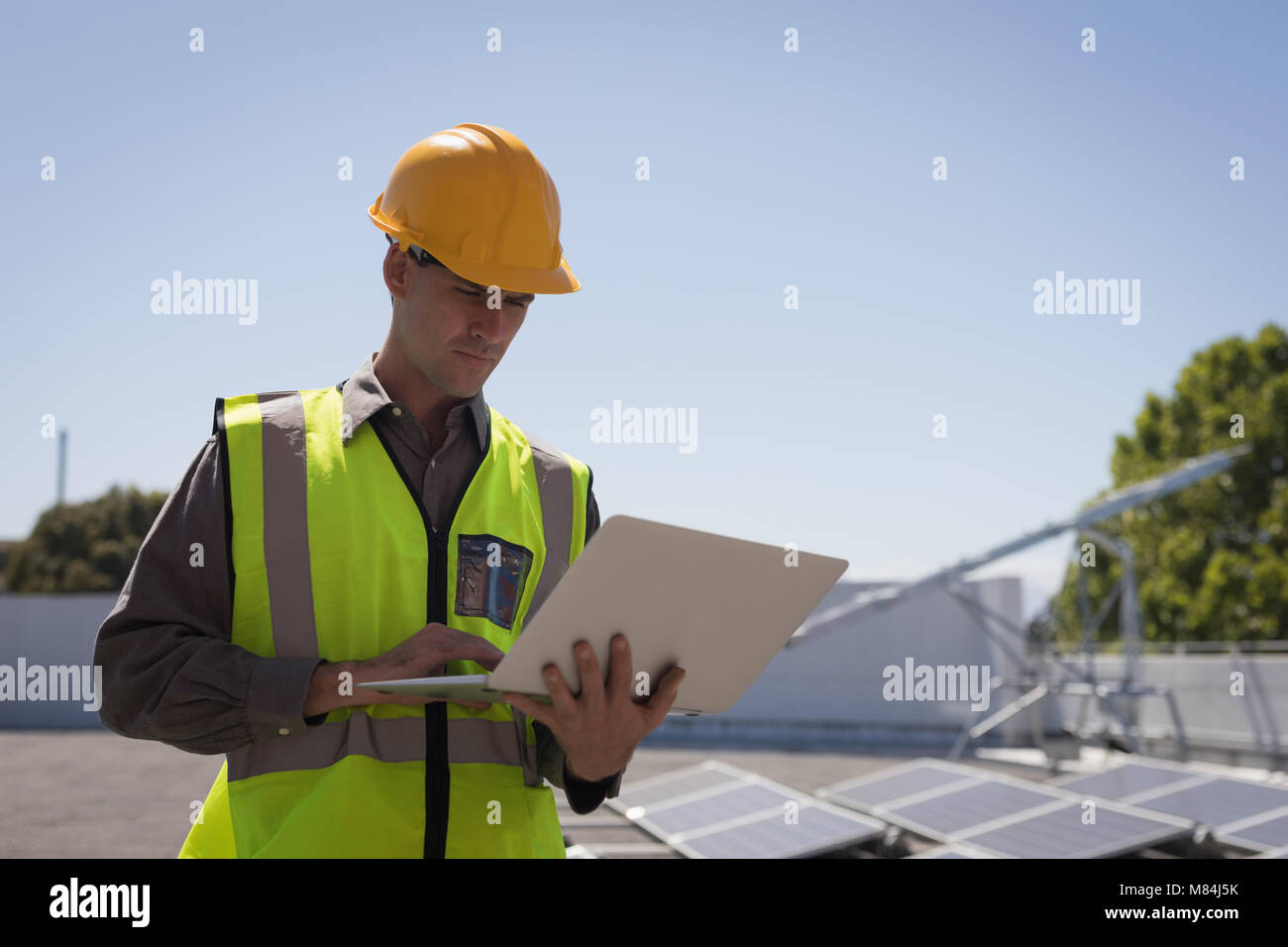 Male worker using laptop at solar station Stock Photo