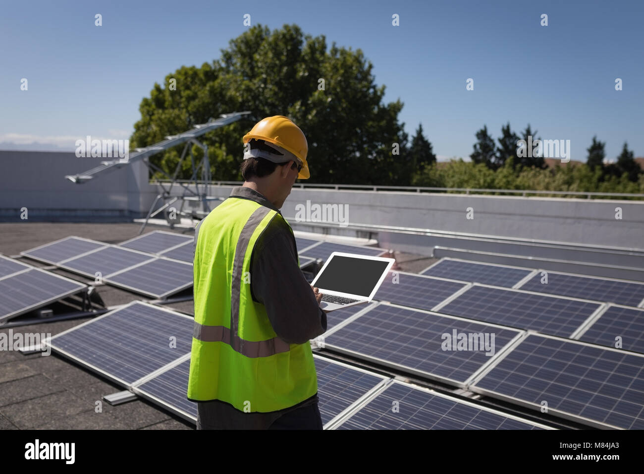 Male worker using laptop at solar station Stock Photo