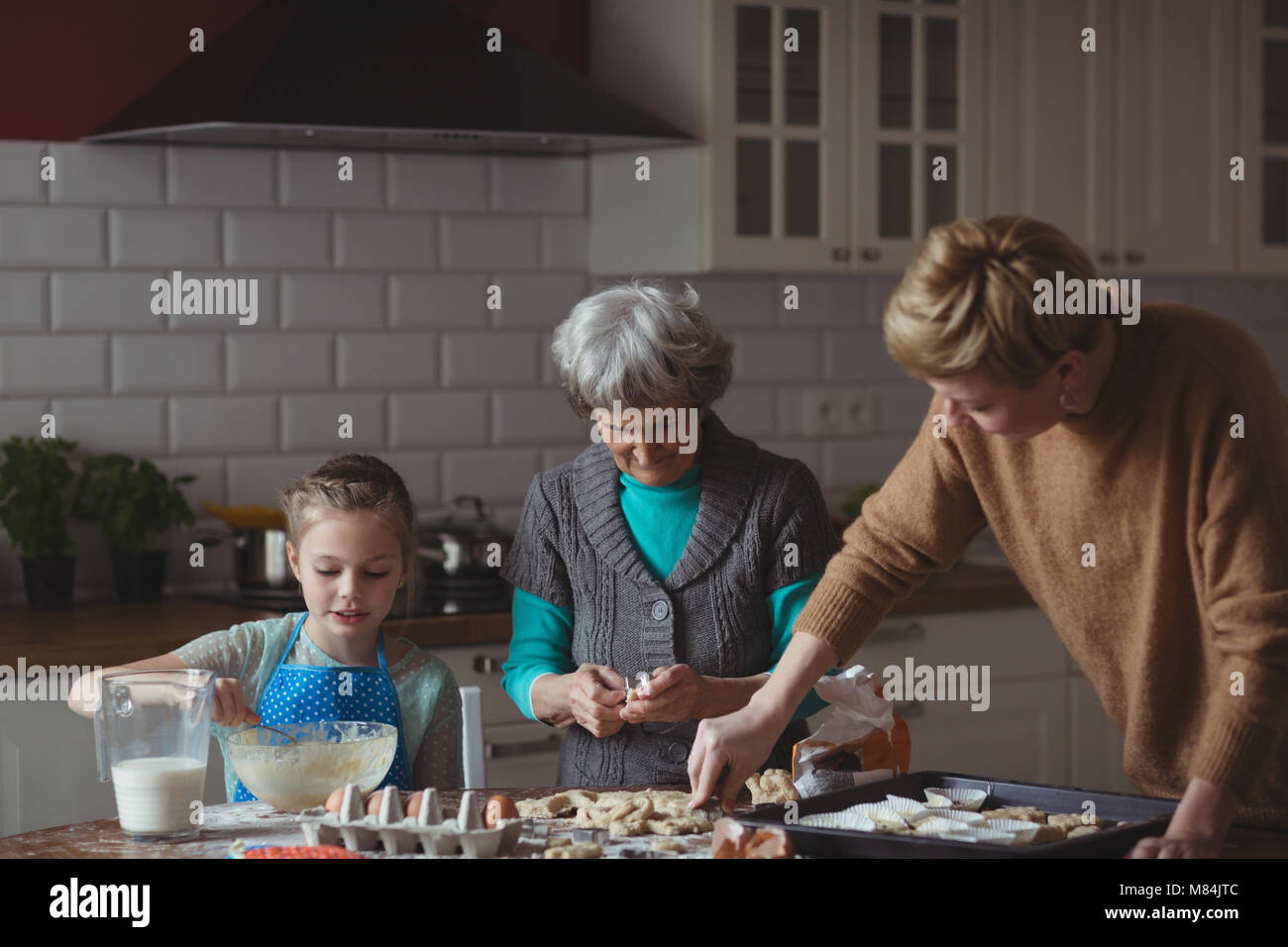 Multi-generation family preparing cupcake in kitchen Stock Photo