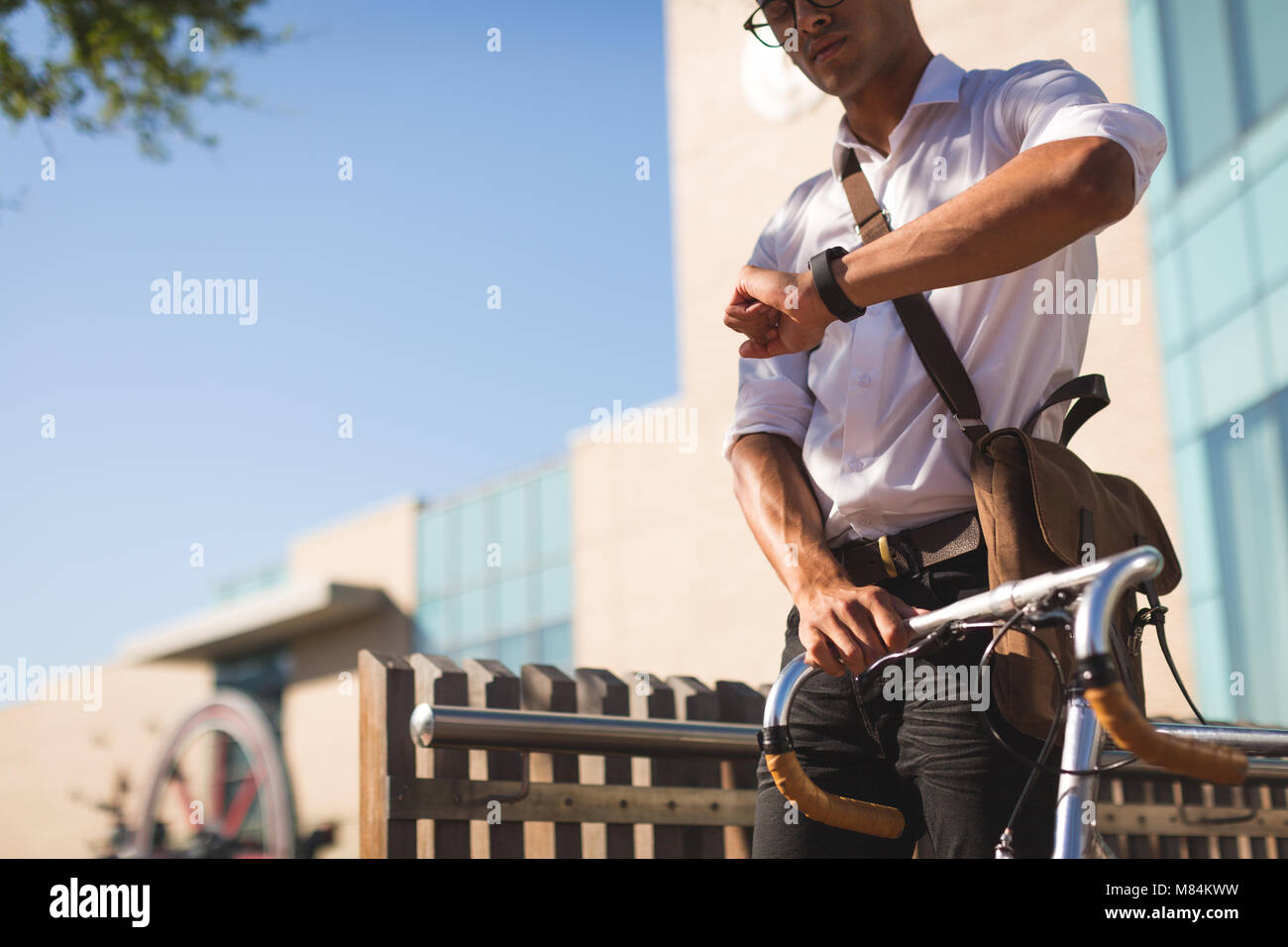 Businessman checking time while walking with his bicycle Stock Photo