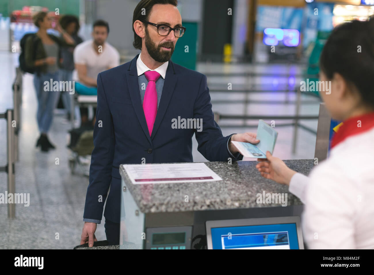 Airline check-in attendant handing passport to commuter Stock Photo