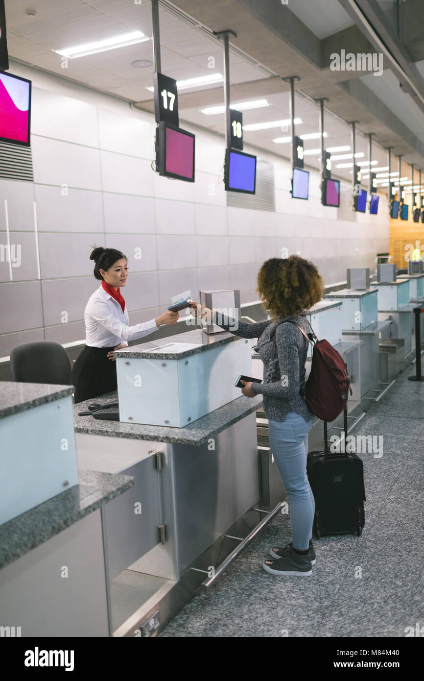 Airline check-in attendant handing passport to commuter Stock Photo