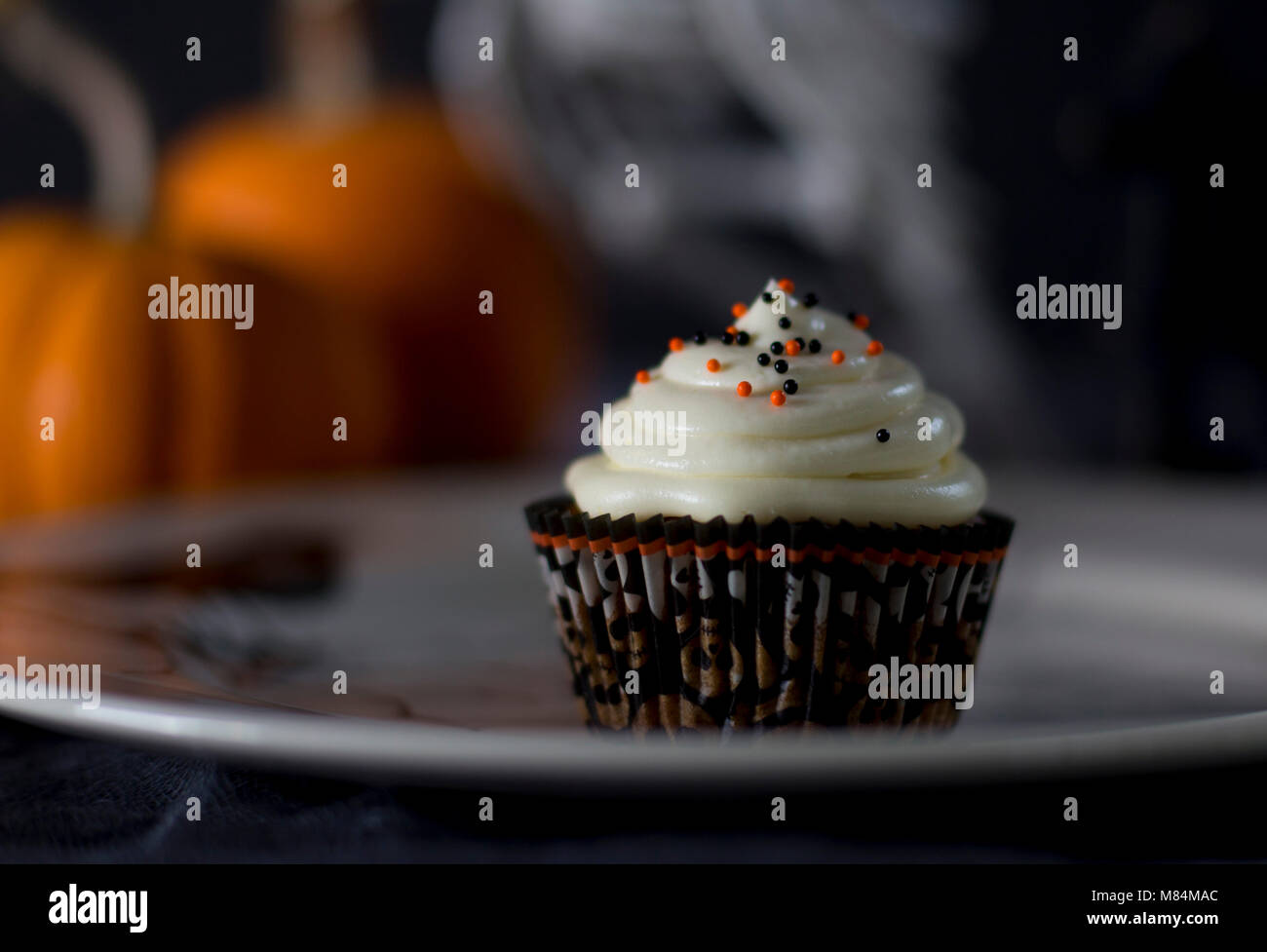 Delicious Pumpkin Halloween Themed Cupcake on a White Plate Stock Photo