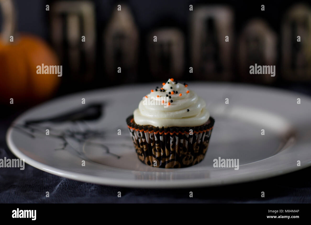 Delicious Pumpkin Halloween Themed Cupcake on a White Plate Stock Photo