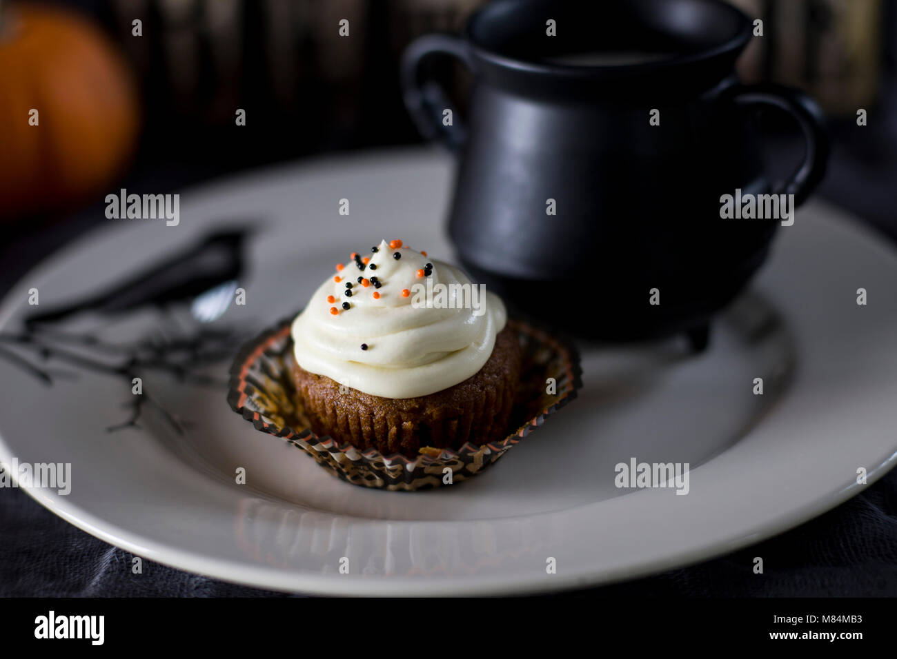 Delicious Pumpkin Halloween Themed Cupcake on a White Plate Stock Photo