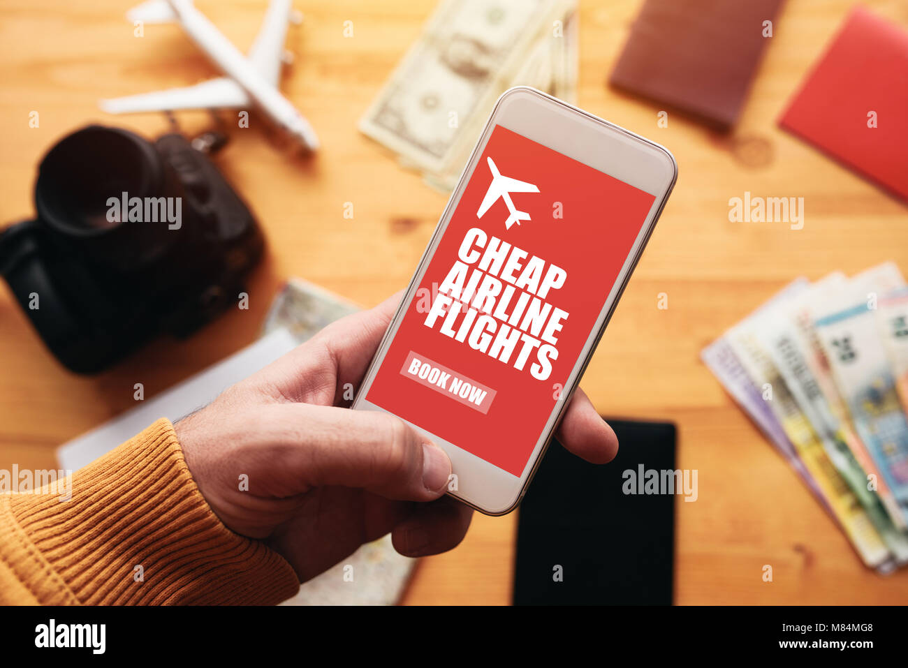 Cheap airline flights online mobile app. Man holding smartphone with mock up application screen related to holiday vacation journey trip. Stock Photo