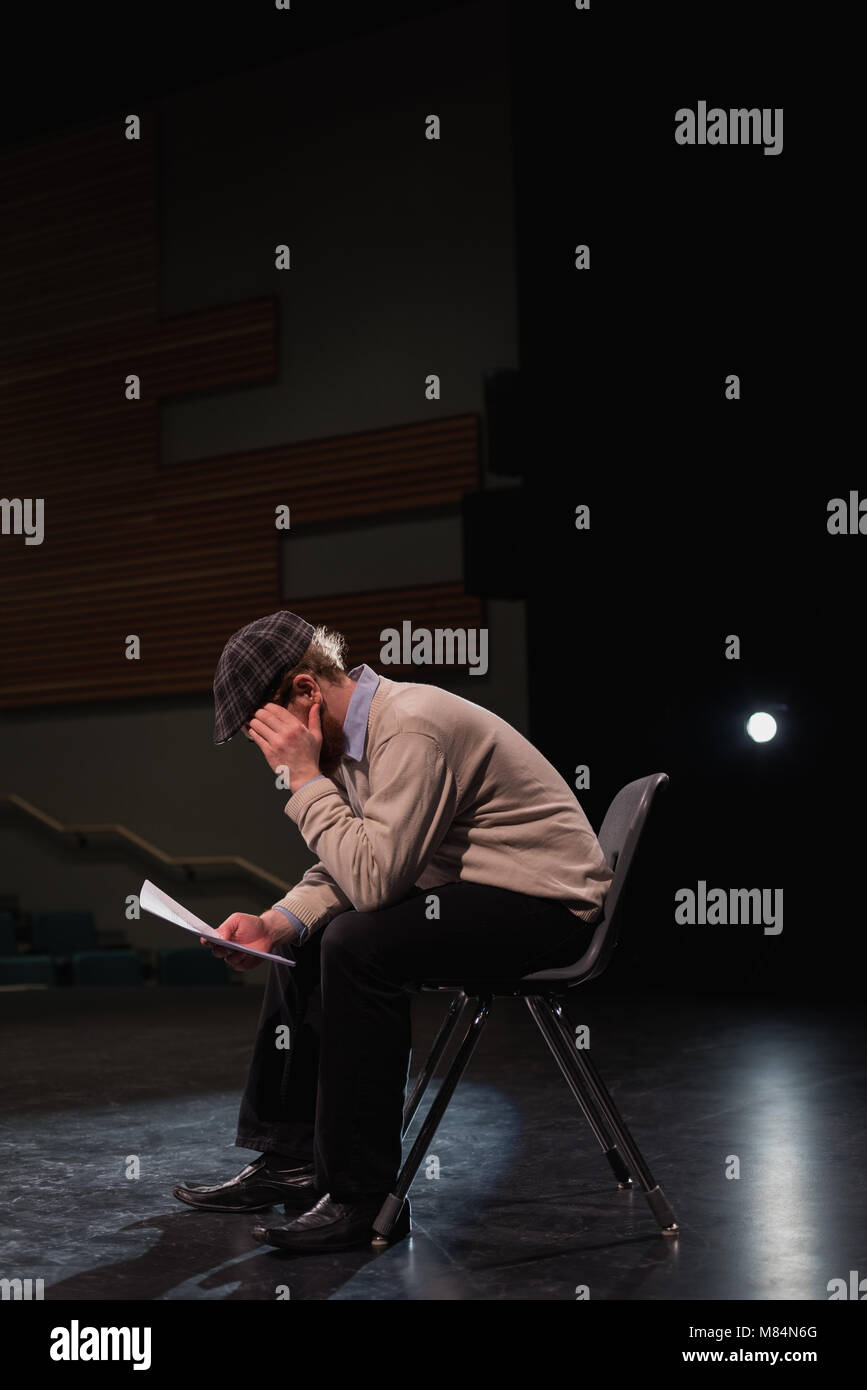 Male actor reading script on stage Stock Photo