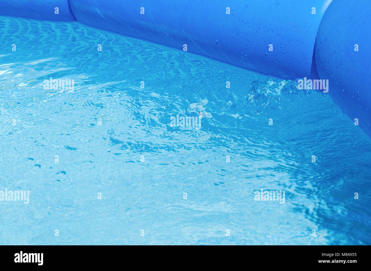 Filled Blue Inflatable Garden Pool with Splashing Water Closeup Stock Photo