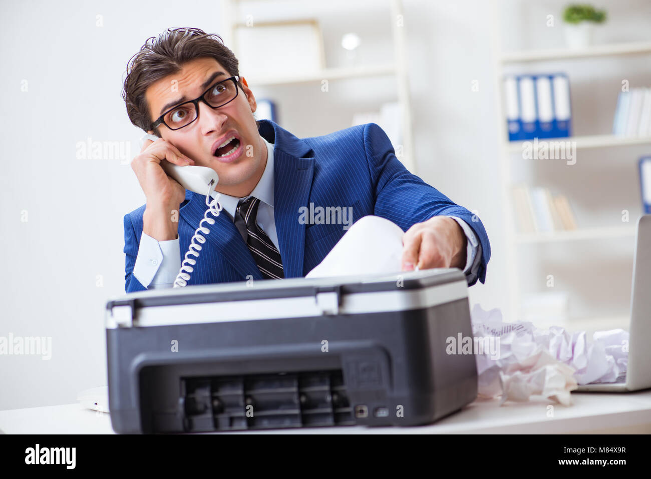 Businessman angry at copying machine jamming papers Stock Photo - Alamy
