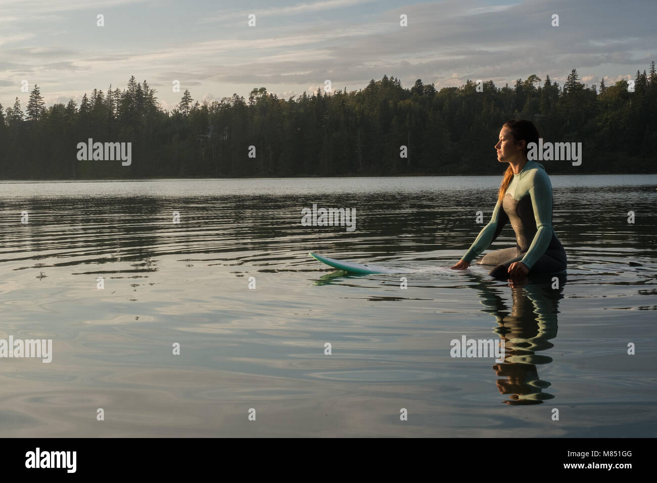 A female surfer watches the sunset while waiting for a wave Stock Photo ...