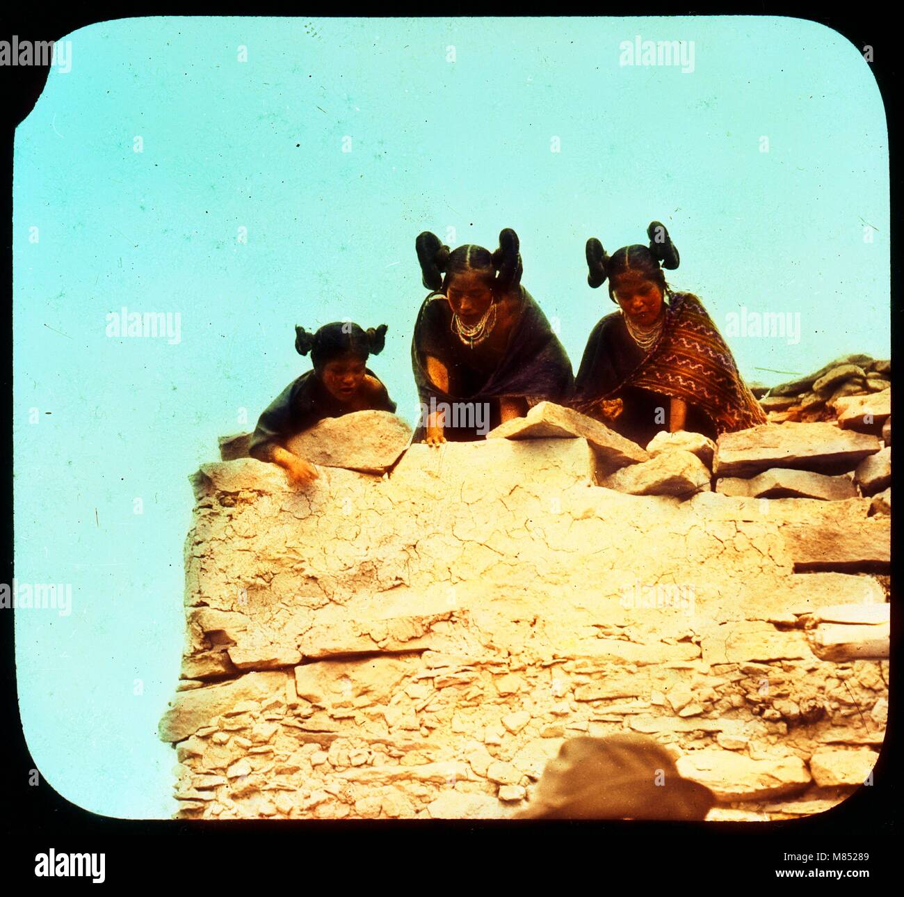 Colorized photo of three Hopi girls with squash blossom whorl