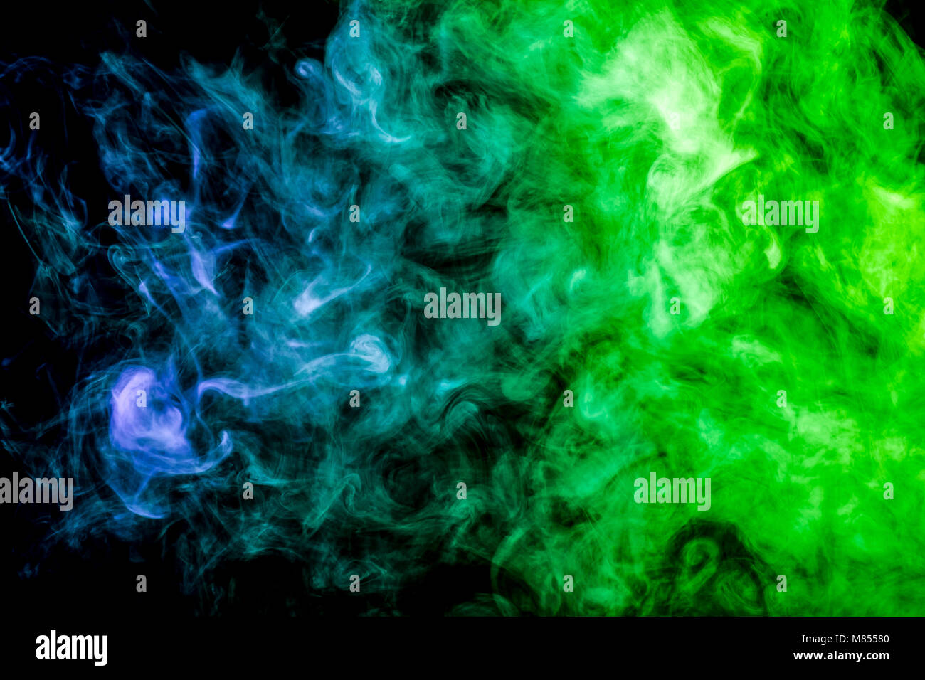 Thick colorful smoke of green and blue on a black isolated background ...