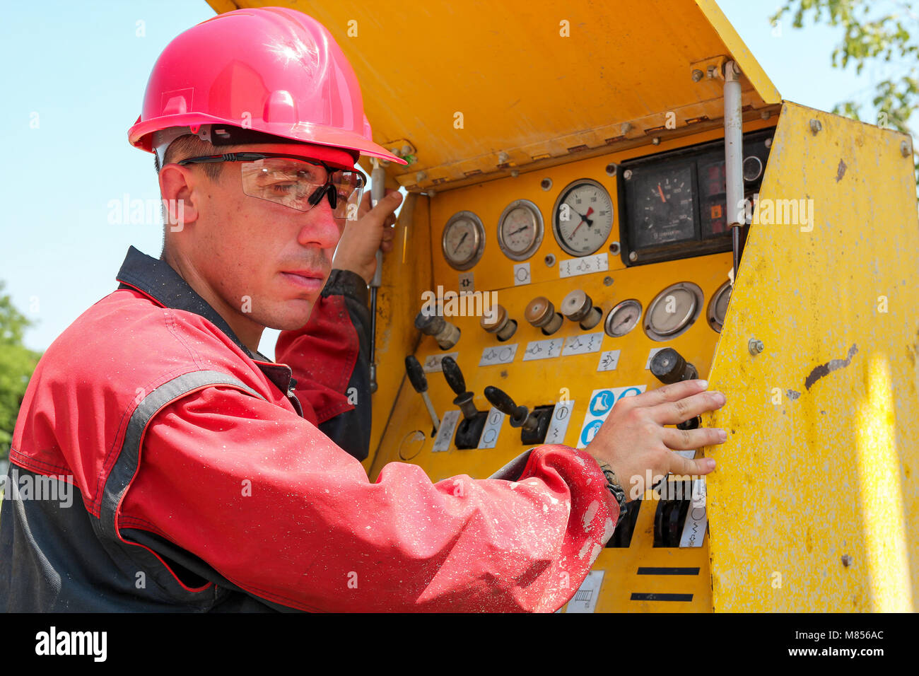 Worker Operating Drilling Rig Control Panel. Oil and gas well drilling worker operates drilling rig machinery. Stock Photo