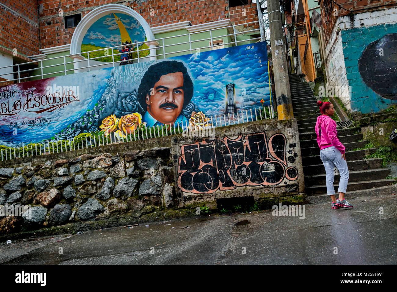A Colombian woman walks along a large mural artwork depicting the lord Pablo Escobar