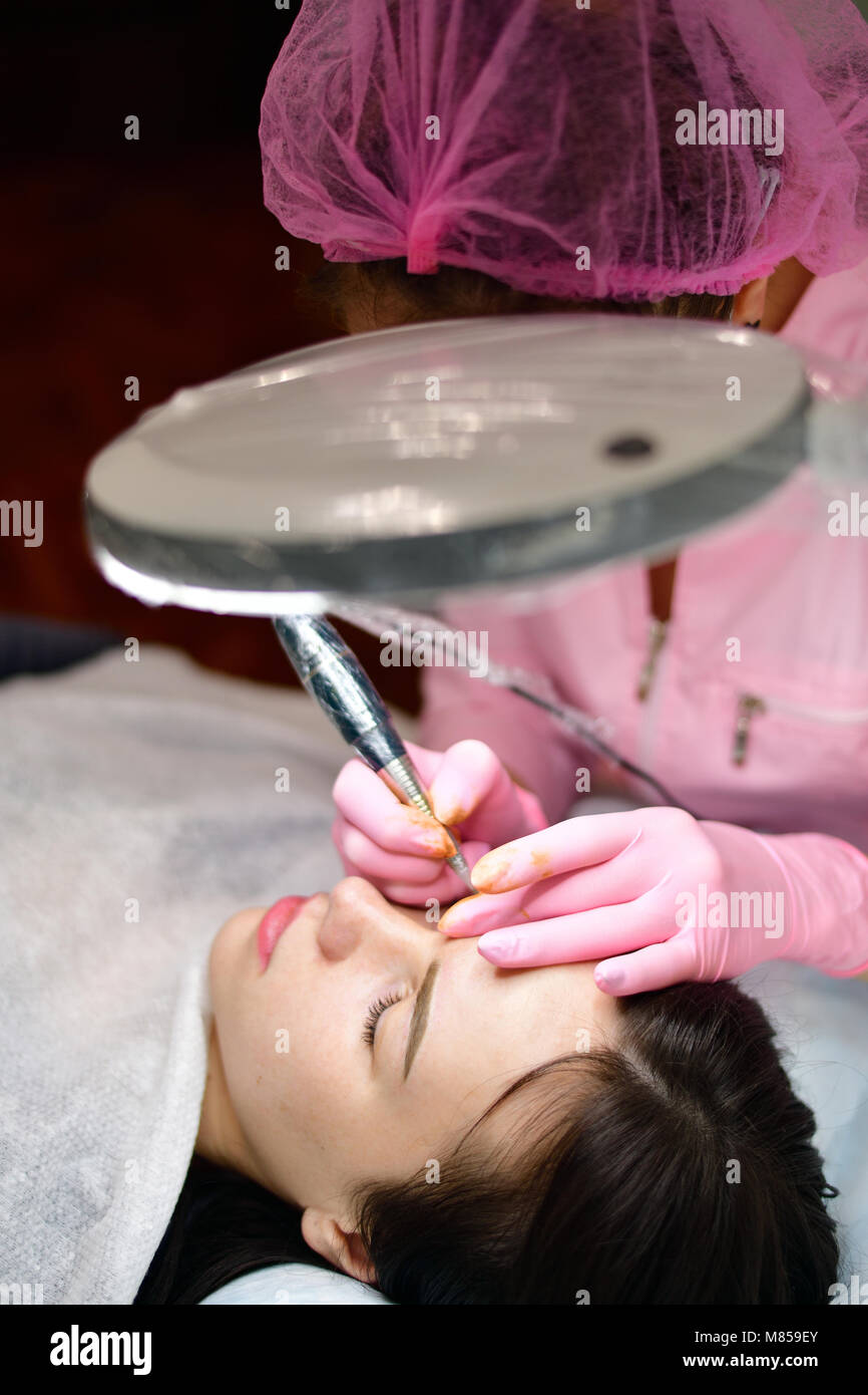 doctor cosmetologist doing instrumental coloring of eyebrows Stock Photo