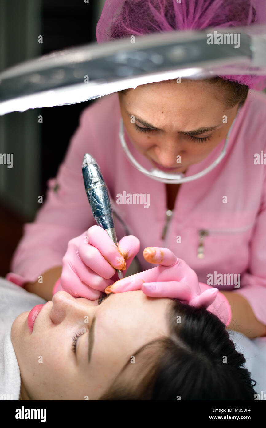 doctor cosmetologist doing instrumental coloring of eyebrows Stock Photo