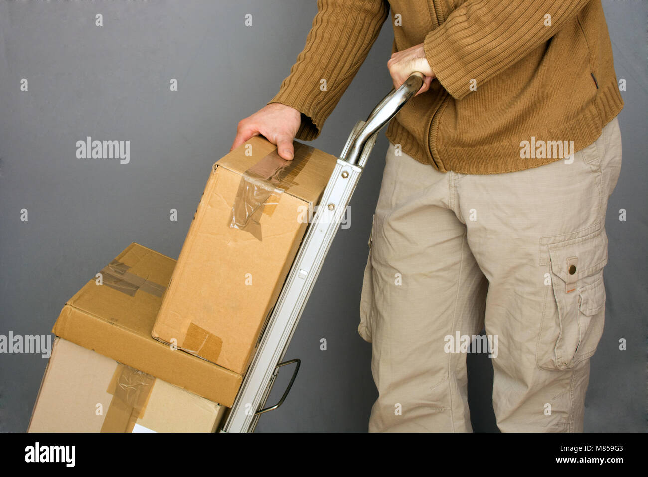 men transporting brown packages on handtruck for shipping Stock Photo