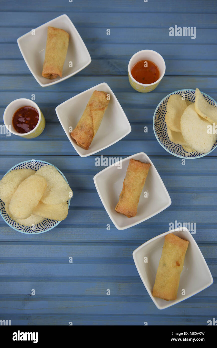 flat lay table of food of prawn crackers and spring rolls with dipping