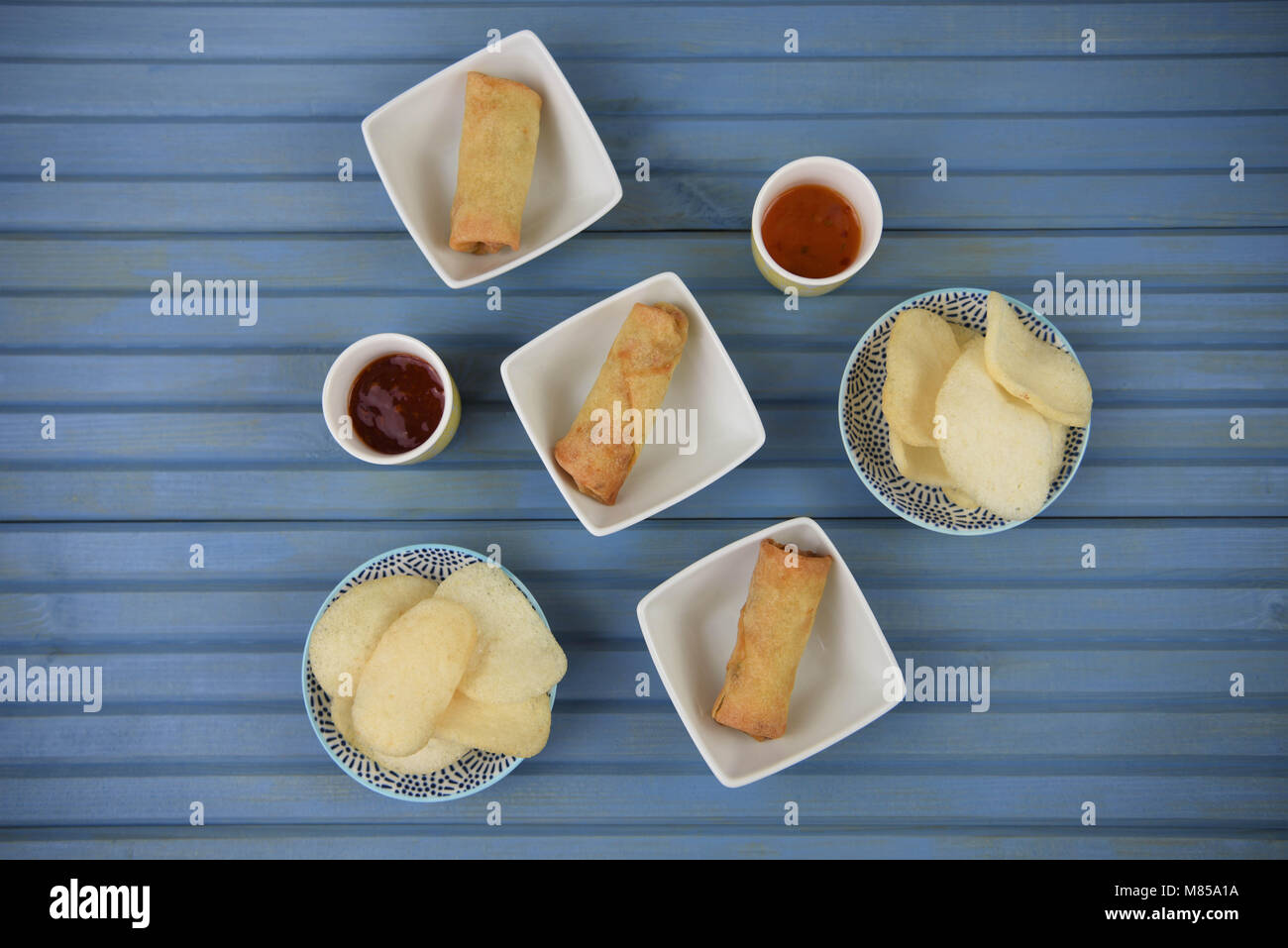 flat lay table of food of prawn crackers and spring rolls with dipping sauce Stock Photo