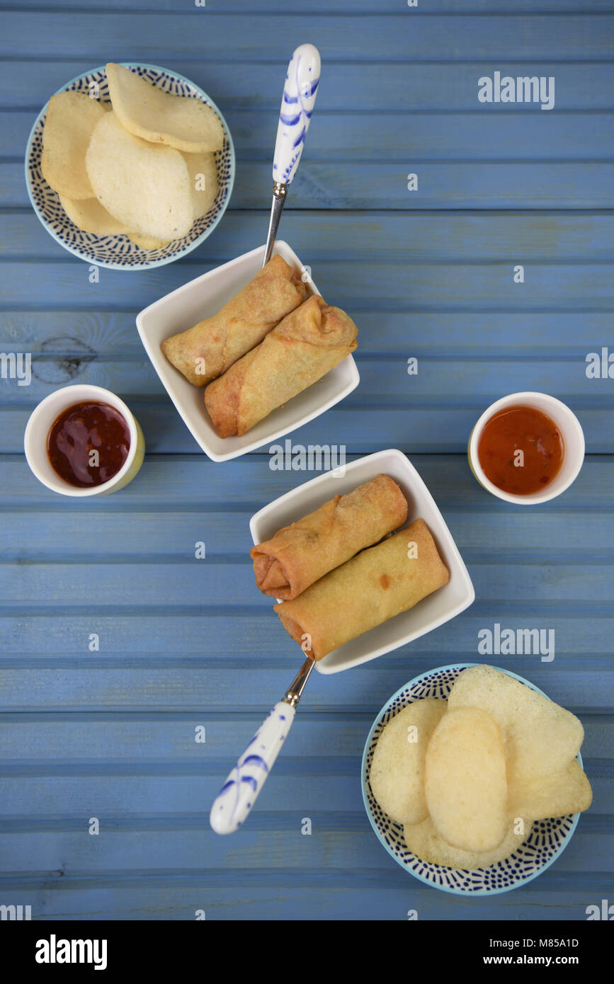 flat lay table of food of prawn crackers and spring rolls with dipping