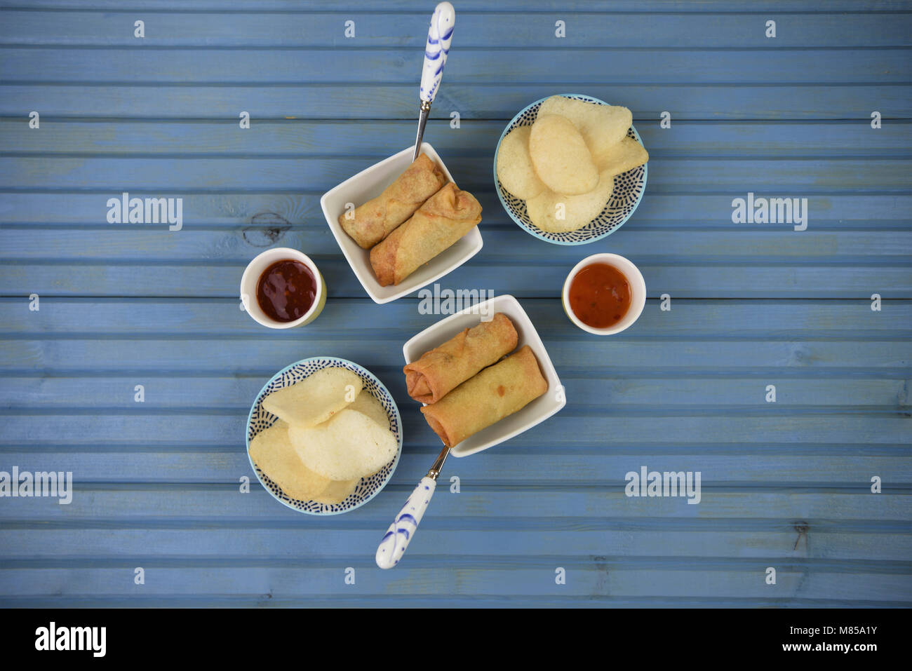 flat lay table of food of prawn crackers and spring rolls with dipping
