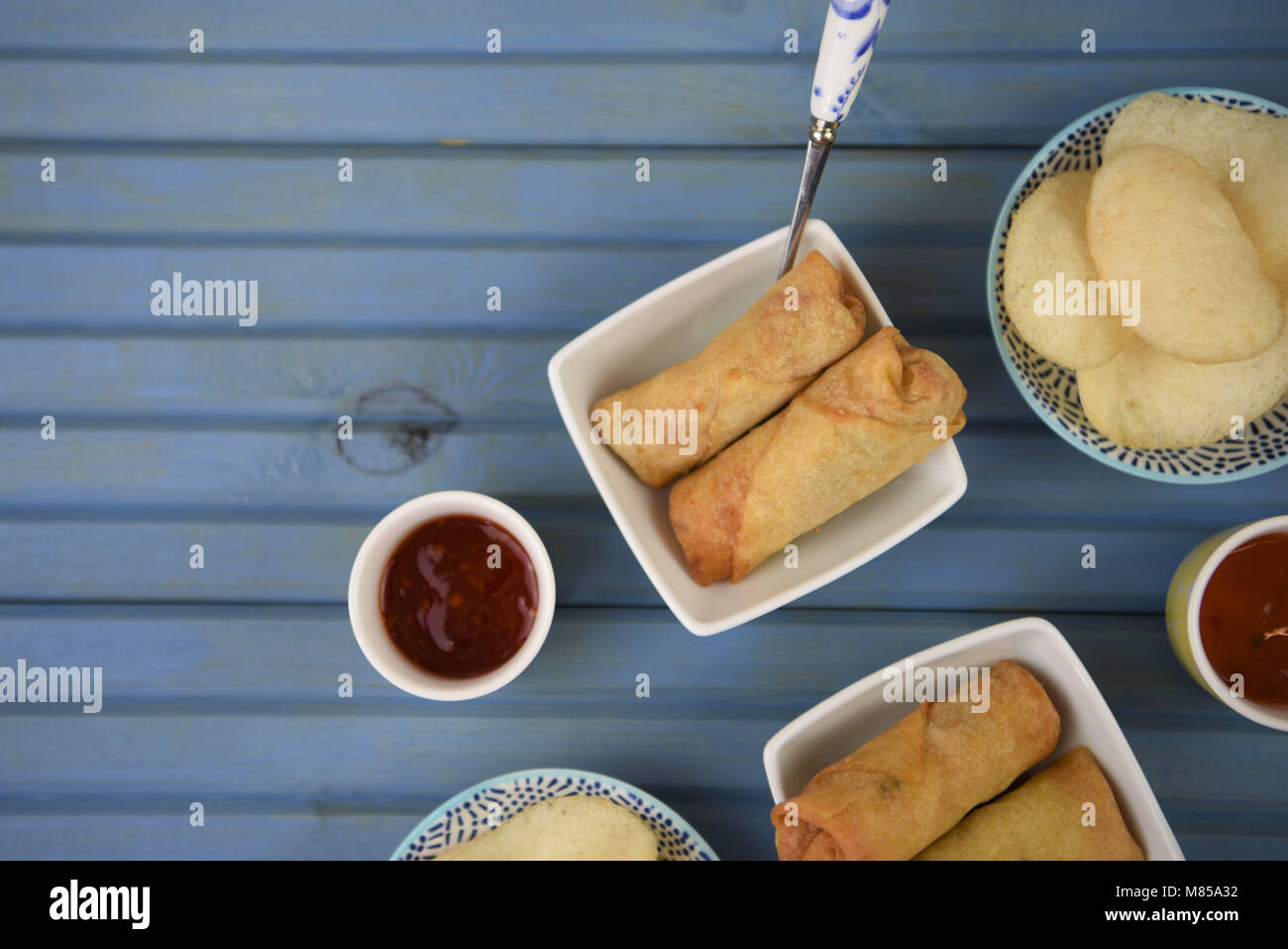 flat lay table of food of prawn crackers and spring rolls with dipping