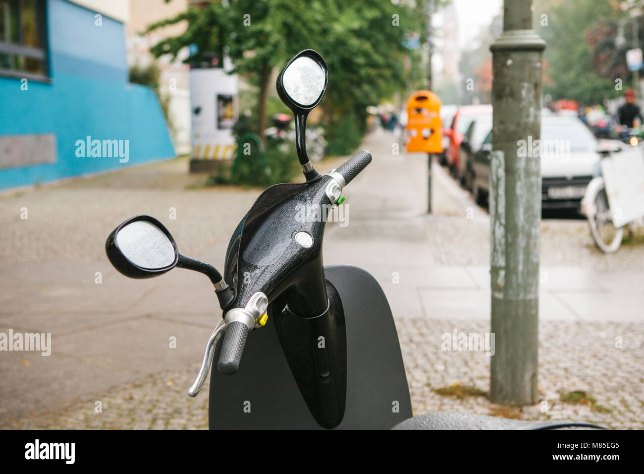 The steering wheel of an electric scooter is in the foreground, in the