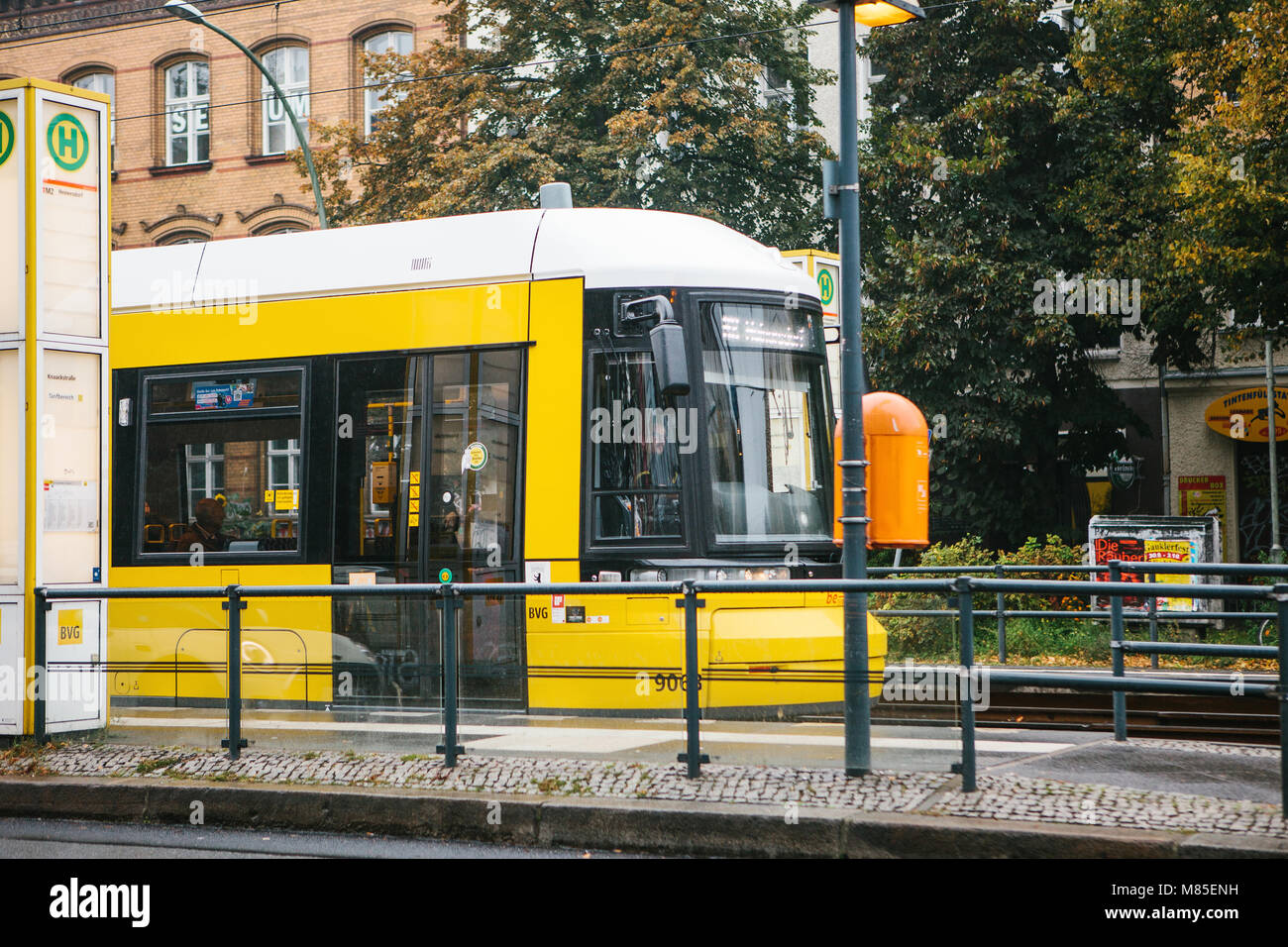 City public transport in Germany. Beautiful black and yellow train stopped at stop on the background of an old building Stock Photo