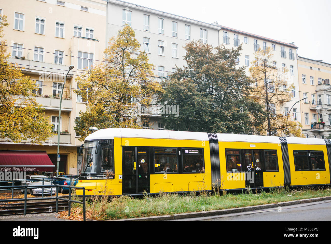 City public transport in Germany. Beautiful black and yellow train stopped at stop on the background of an old building Stock Photo