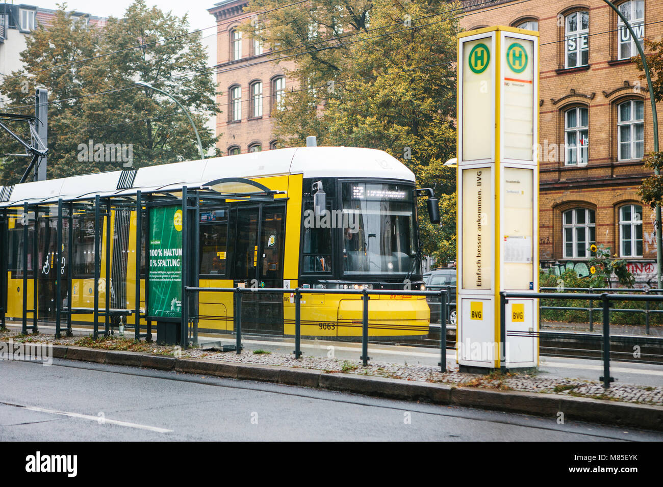 City public transport in Germany. Beautiful black and yellow train stopped at stop on the background of an old building Stock Photo